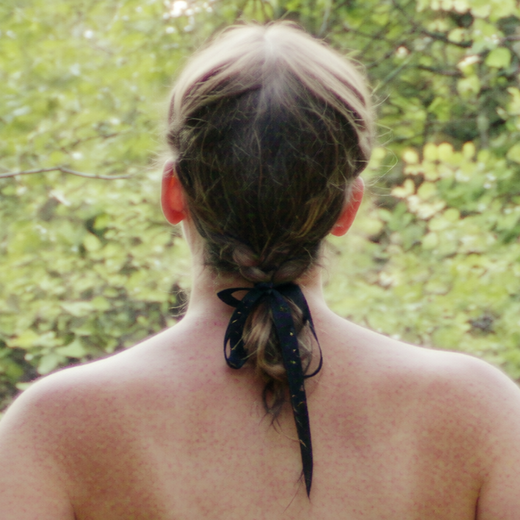 Back view of woman with braided hair tied with ribbon