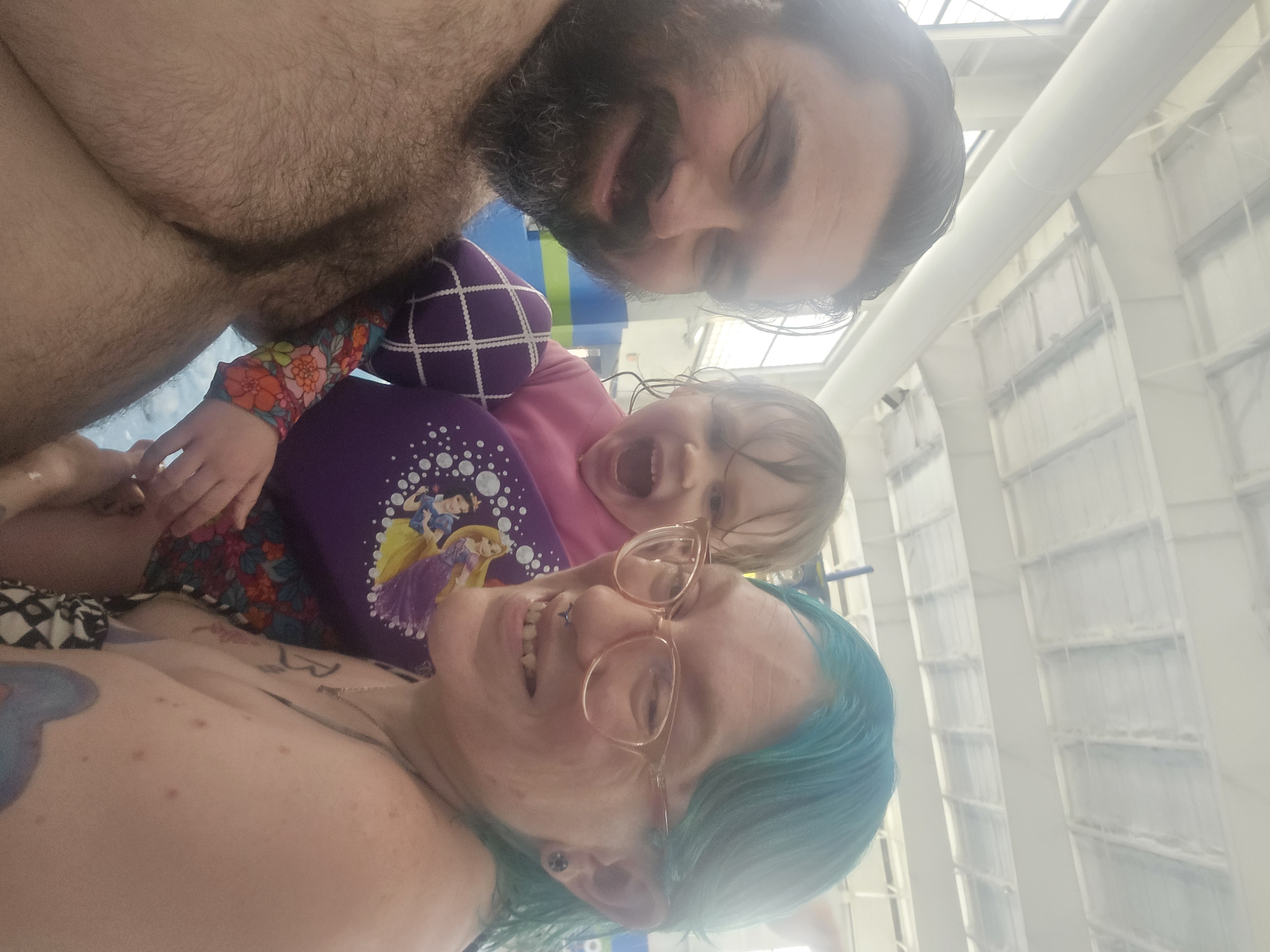 Pixar-style 3D family at sunny outdoor water park, bearded dad, mom with teal-blue hair and pink glasses, toddler with…